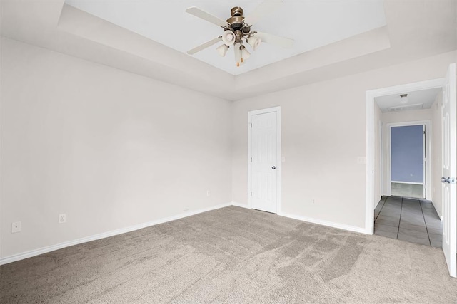 spare room with carpet, ceiling fan, and a raised ceiling