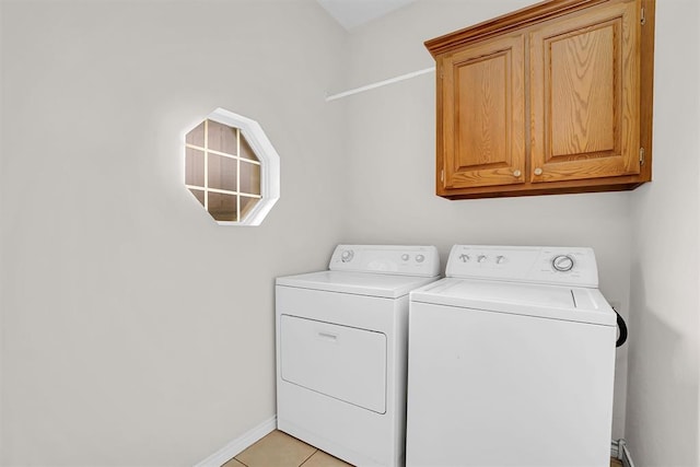 clothes washing area with cabinets, light tile patterned floors, and washing machine and clothes dryer