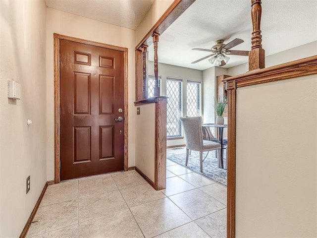 entryway featuring ceiling fan, light tile patterned floors, and a textured ceiling