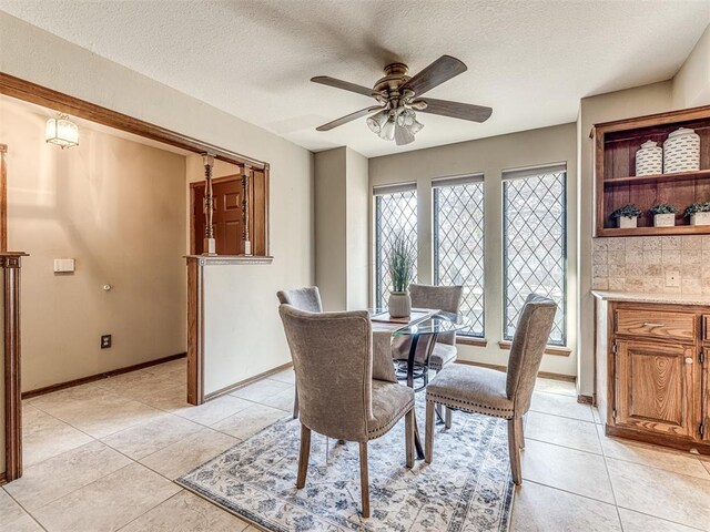 tiled dining room with a textured ceiling and ceiling fan