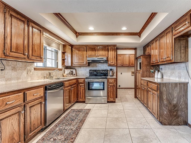 kitchen with sink, stainless steel appliances, a tray ceiling, light tile patterned floors, and ornamental molding