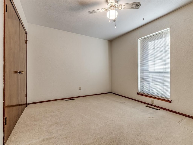 carpeted empty room with a textured ceiling and ceiling fan