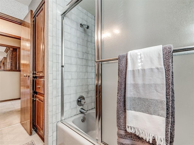 bathroom with combined bath / shower with glass door and tile patterned flooring