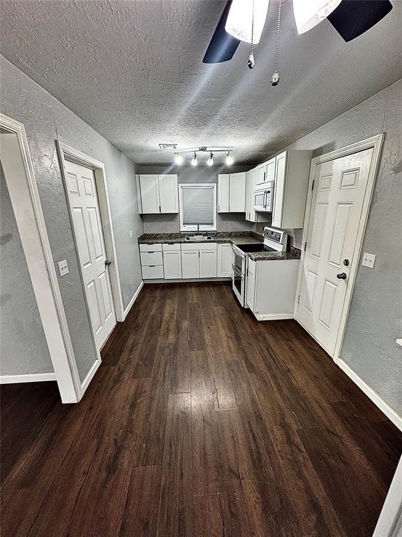 kitchen featuring dark wood-type flooring, white cabinets, rail lighting, sink, and white electric stove