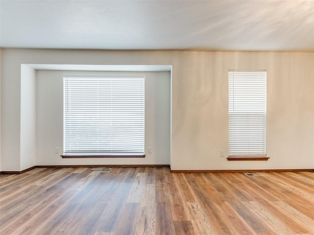 spare room with a wealth of natural light and hardwood / wood-style flooring