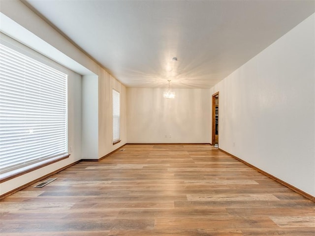 spare room with a chandelier and light hardwood / wood-style floors