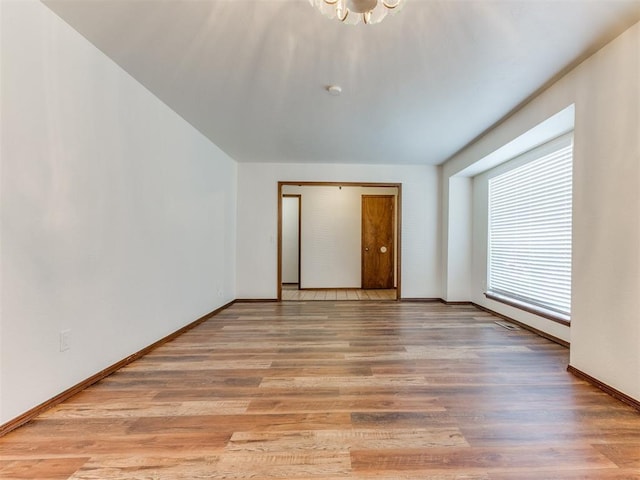 spare room with a chandelier and light hardwood / wood-style flooring