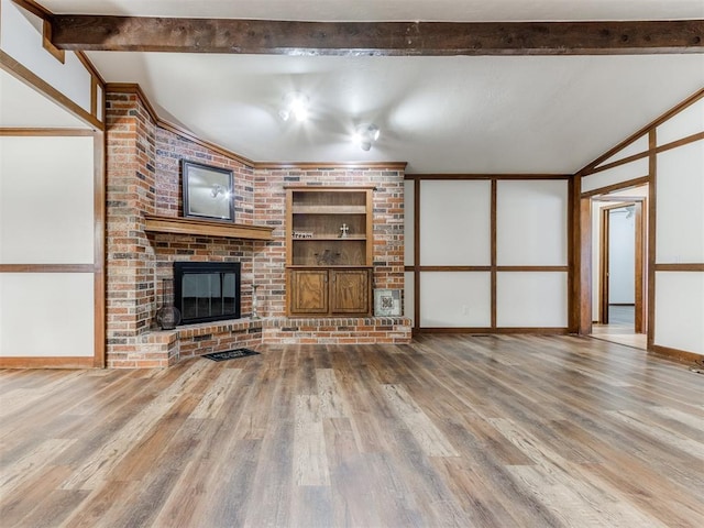 unfurnished living room with beam ceiling, a fireplace, and hardwood / wood-style flooring