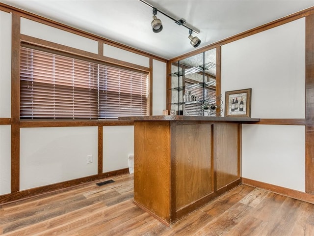 bar with rail lighting and light wood-type flooring