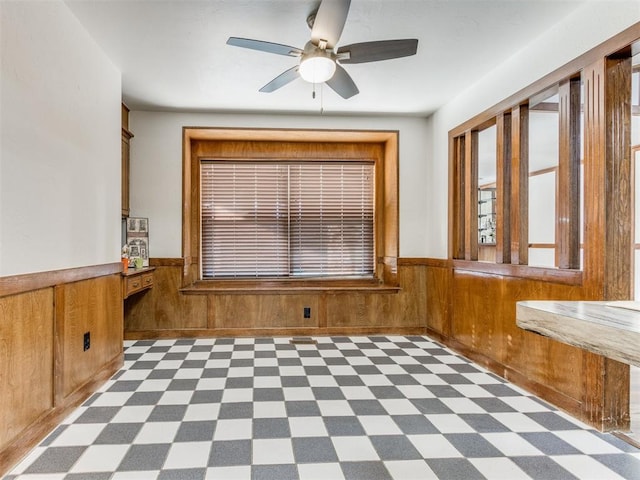 unfurnished dining area featuring ceiling fan and wooden walls