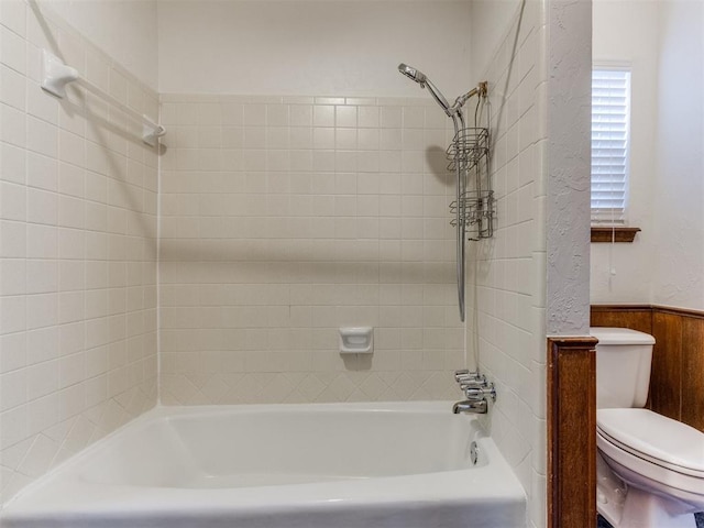 bathroom featuring toilet and tiled shower / bath