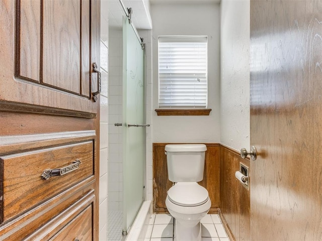 bathroom featuring tile patterned floors, wood walls, toilet, and walk in shower