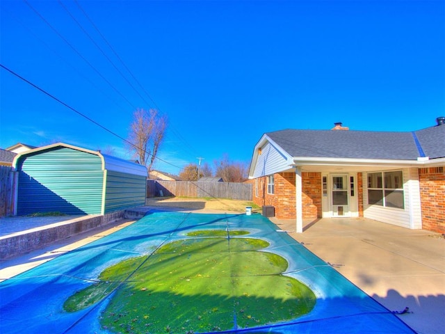 view of pool with a storage shed and a patio