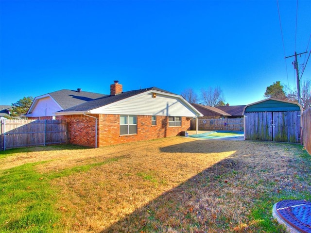 rear view of house with a shed, a yard, and a fenced in pool