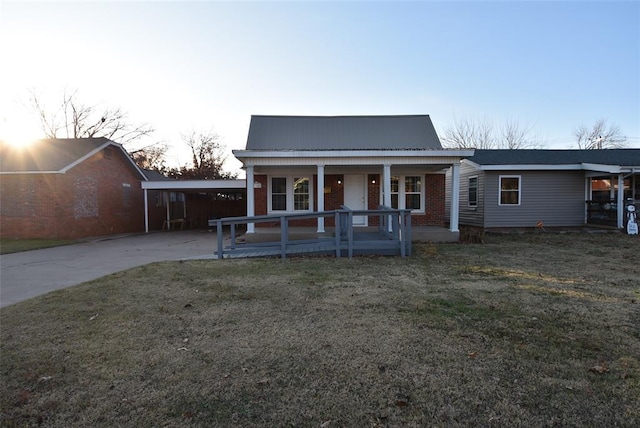 view of front of home with a lawn, a porch, and a carport