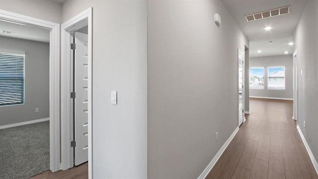 hallway featuring dark wood-style flooring, visible vents, and baseboards