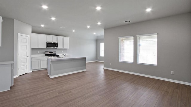 kitchen with white cabinets, an island with sink, appliances with stainless steel finishes, open floor plan, and light countertops