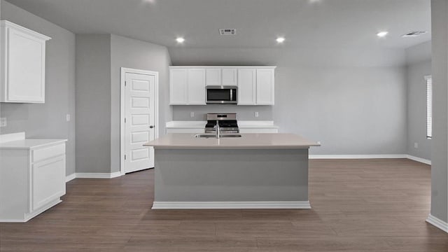 kitchen featuring an island with sink, white cabinets, stainless steel appliances, and light countertops