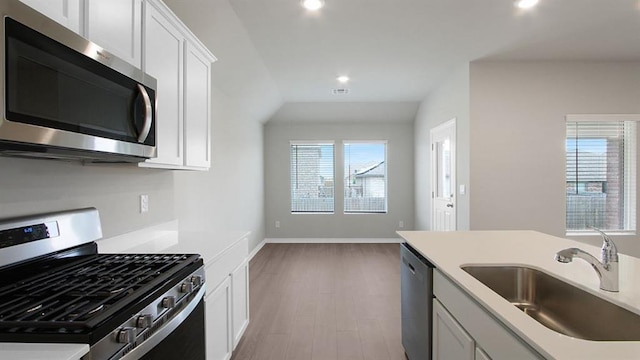 kitchen with recessed lighting, stainless steel appliances, a sink, white cabinetry, and light countertops