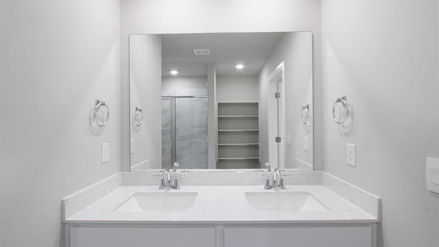 full bathroom featuring double vanity, a shower stall, and a sink