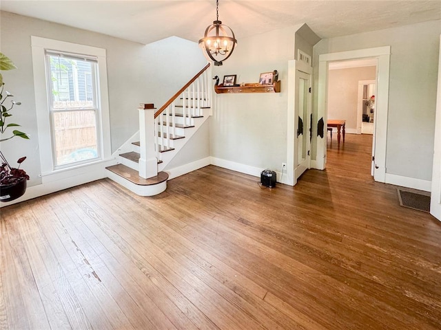 foyer entrance with a chandelier and wood-type flooring