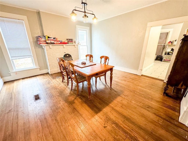 dining space featuring a chandelier, light wood-type flooring, plenty of natural light, and ornamental molding