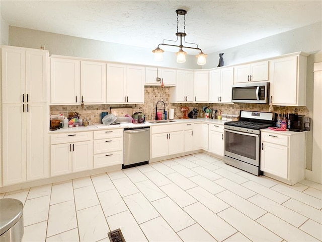 kitchen featuring decorative light fixtures, backsplash, stainless steel appliances, and sink