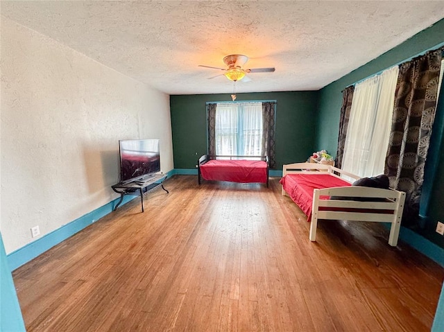 bedroom with hardwood / wood-style flooring, ceiling fan, and a textured ceiling