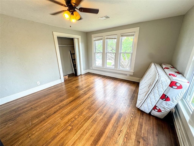 unfurnished bedroom with a closet, ceiling fan, and dark wood-type flooring