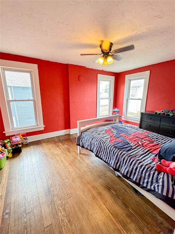 bedroom featuring ceiling fan, wood-type flooring, and a textured ceiling