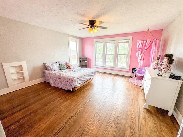 bedroom featuring ceiling fan, wood-type flooring, and a textured ceiling