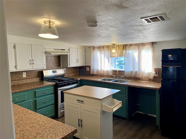 kitchen with black fridge, sink, gas range, a kitchen island, and white cabinetry