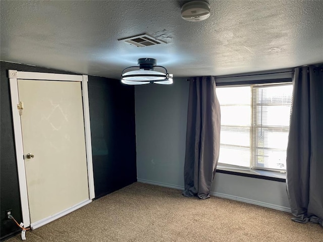 carpeted empty room featuring a textured ceiling