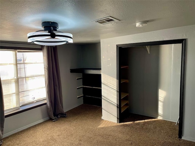 unfurnished bedroom with carpet flooring, a textured ceiling, and a closet