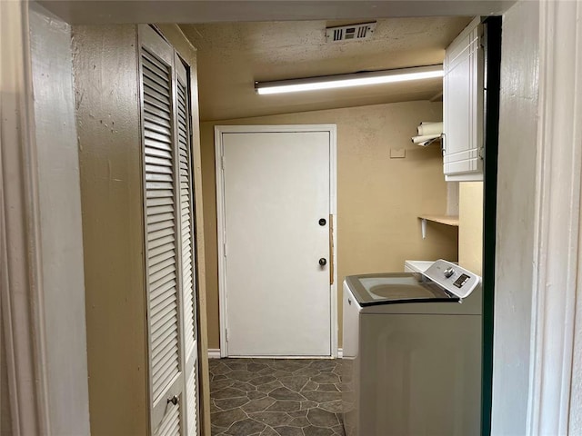 laundry room featuring dark tile patterned floors, cabinets, and washer / dryer