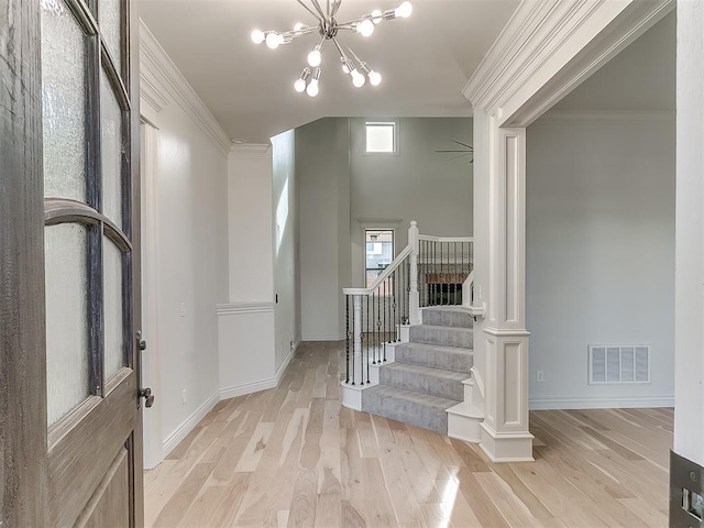 entrance foyer with light wood-type flooring, an inviting chandelier, and crown molding