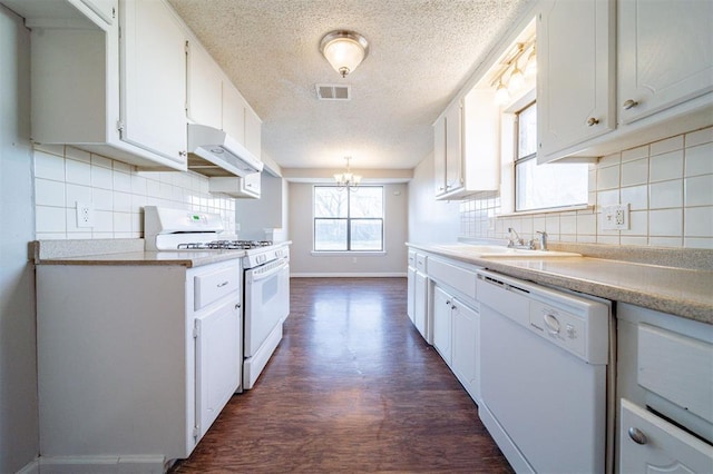 kitchen with white cabinetry, sink, dark hardwood / wood-style flooring, white appliances, and an inviting chandelier