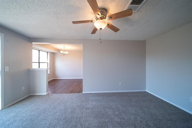 empty room with ceiling fan with notable chandelier, a textured ceiling, and dark carpet