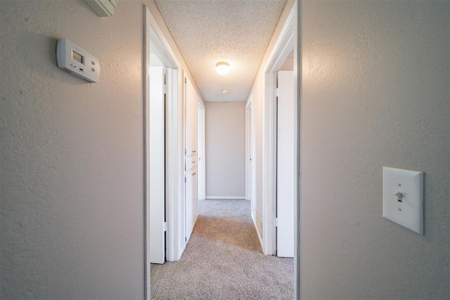 hallway with light carpet and a textured ceiling