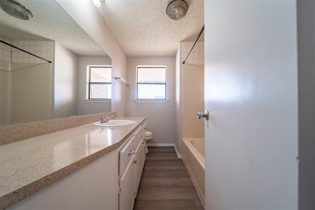 full bathroom featuring shower / bathtub combination, hardwood / wood-style flooring, vanity, toilet, and a textured ceiling