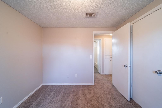 unfurnished room featuring light carpet and a textured ceiling