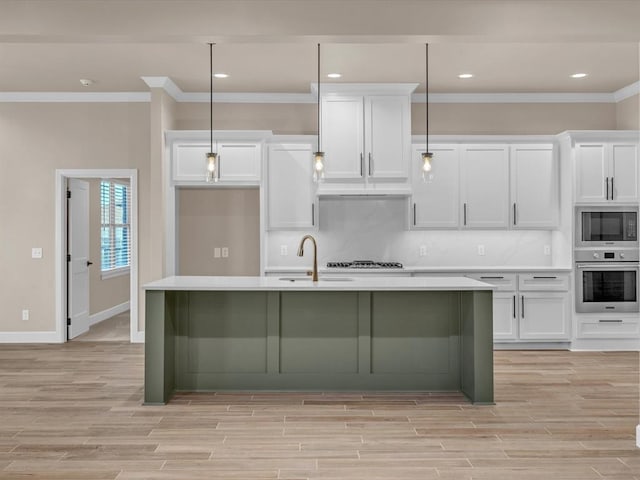 kitchen featuring decorative light fixtures, oven, and a kitchen island with sink