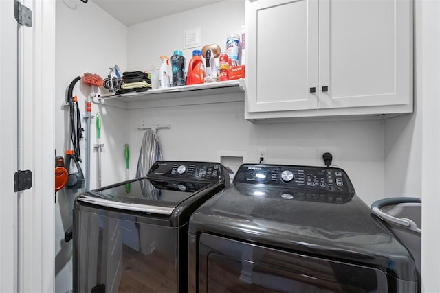 washroom featuring cabinets, hardwood / wood-style floors, and washing machine and clothes dryer