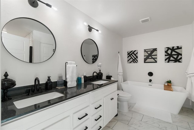 bathroom with vanity, a tub to relax in, and toilet