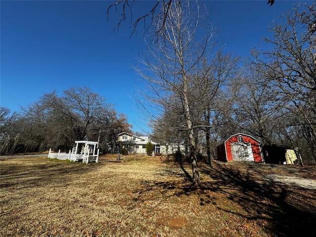 view of yard featuring driveway, a detached garage, and an outbuilding