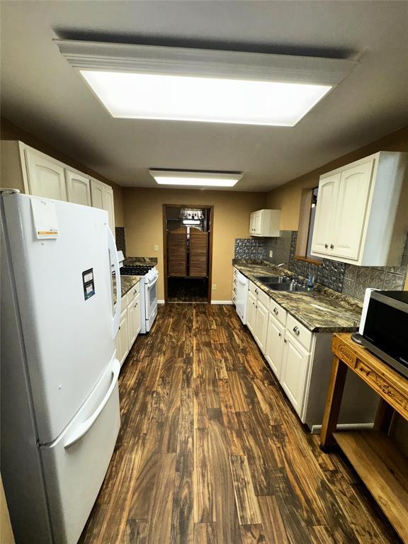 kitchen with white appliances, decorative backsplash, dark wood finished floors, and white cabinets