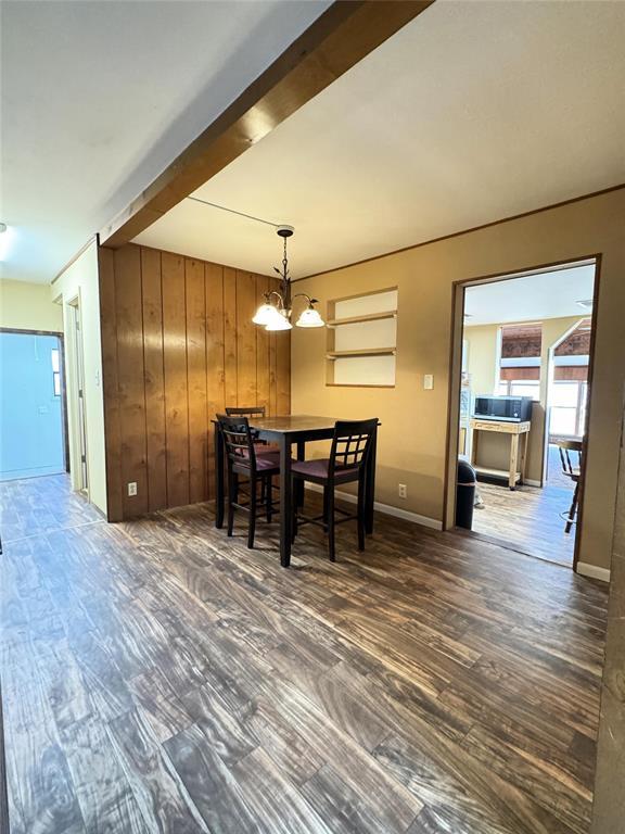 dining space with an inviting chandelier, wooden walls, and dark hardwood / wood-style flooring