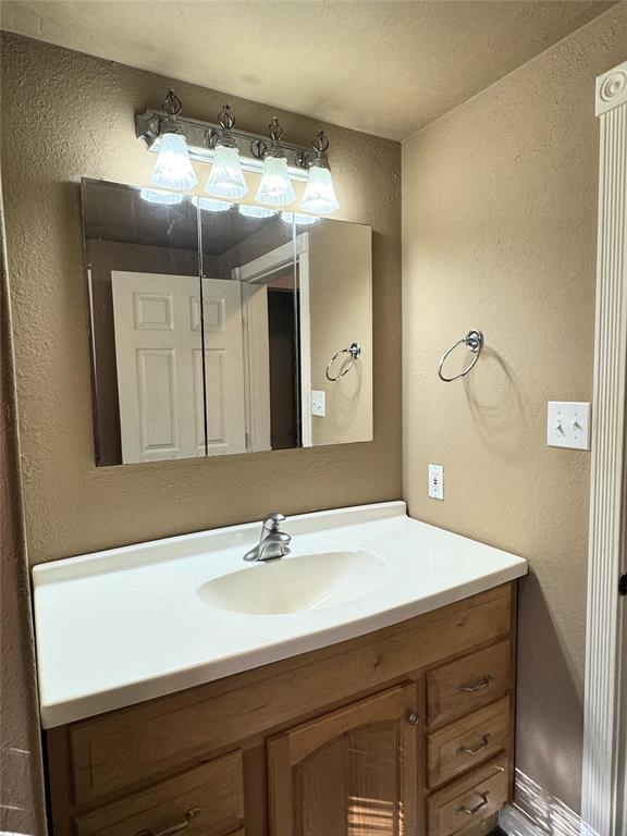 bathroom with a textured wall and vanity