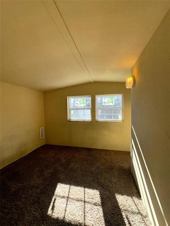 carpeted empty room with lofted ceiling and visible vents