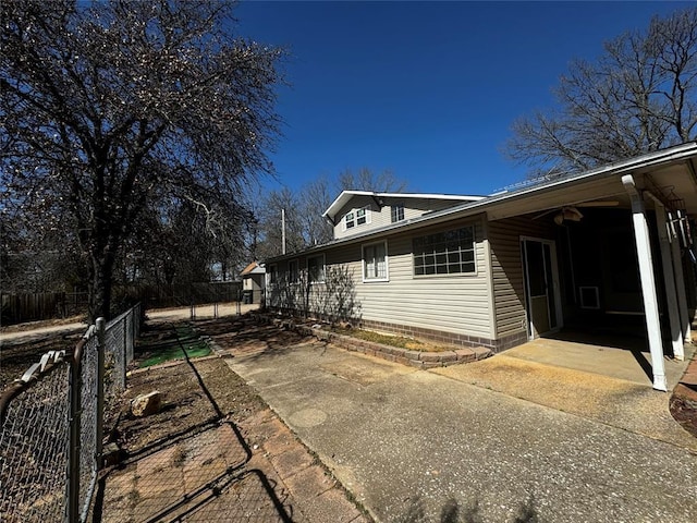 view of side of home with a carport, a patio area, and fence